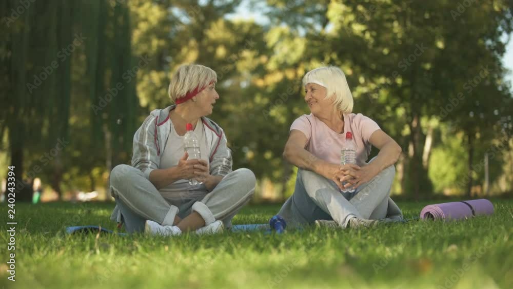 Middle age woman and her mother talking after doing exercises and yoga in park Middle age woman and her mother talking after doing exercises and yoga in park