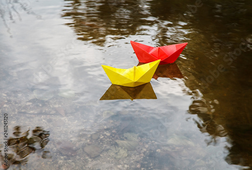 Fototapeta Naklejka Na Ścianę i Meble -  two multicolored paper boats floating on a stream
