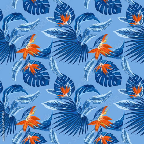 seamless pattern of tropical blue palm leaves, monstera leaves and coral flowers of the bird of paradise (Strelitzia) plumeria on a light blue background. Wallpaper trend design.