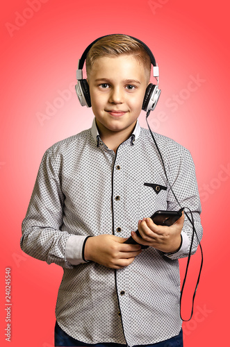 The boy listens to music with headphones with the phone in hands