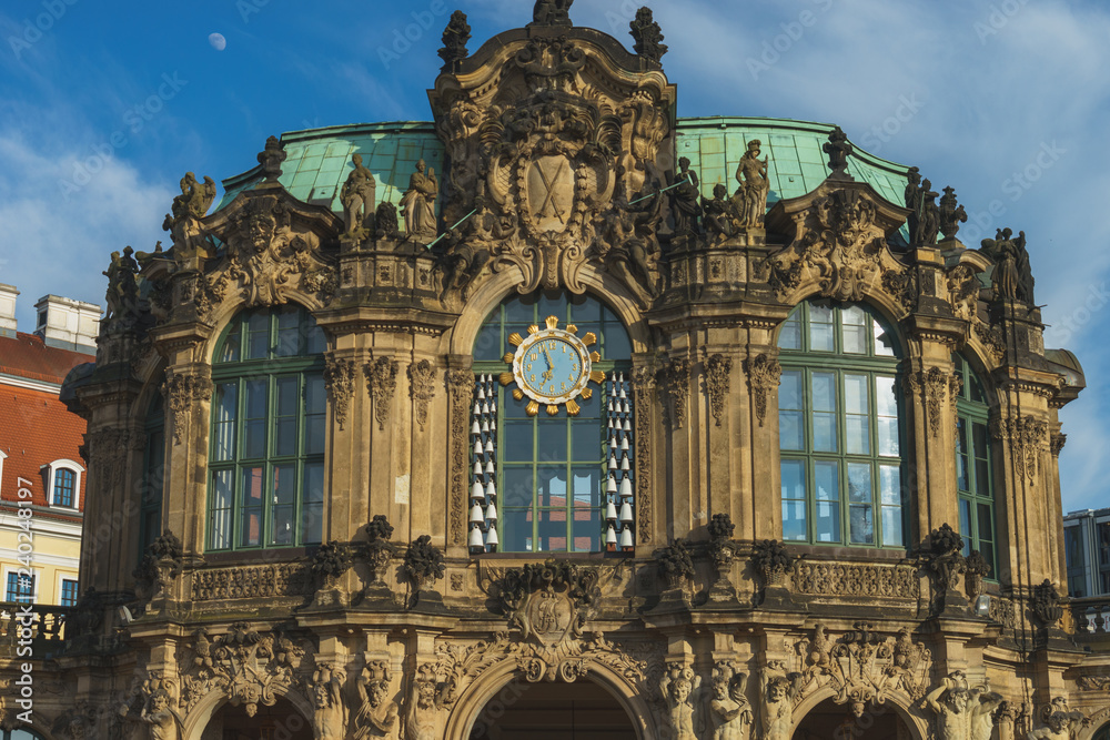 Fototapeta premium das Glockenspiel Tor des Dresdner Zwinger in der Abendsonnen. Das baroke Gebäude steht vor einem blauen Abendhimmel mit Mond.