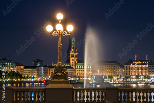 The Inner Alster Lake (German: Binnenalster) in Hamburg, Germany. View of the city at night with the fountain reflecting in the water and the Renaissance Revival Lombard Bridge (Lombardsbruecke). photo