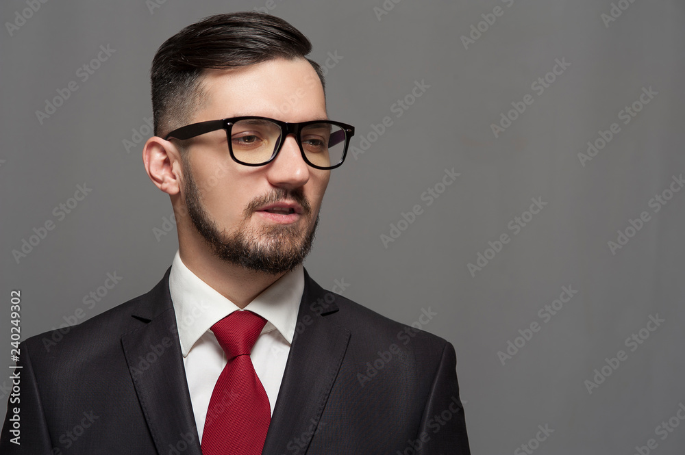 Stylish businessman in formal suit and glasses posing on gray background Stylish businessman in formal suit and glasses posing on gray background