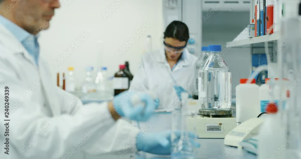 Portrait of male scientist with a pipette analyzes a liquid to extract the DNA and molecules in the test tubes in laboratory. Shot in 8K. Concept: research,biochemistry, pharmaceutical medicine Portrait of male scientist with a pipette analyzes a liquid to extract the DNA and molecules in the test tubes in laboratory. Shot in 8K. Concept: research,biochemistry, pharmaceutical medicine