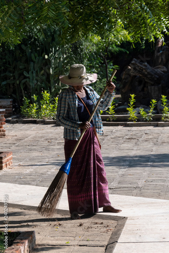 Señora limpiando con una escoba un piso en exterior de un templo en Bagan. Myanmar