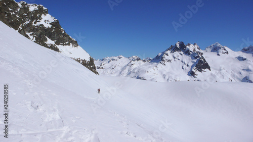 backcountry skier hiking along a snow slope on his way to a high alpine mountain peak