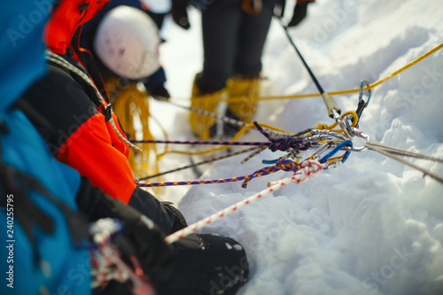 A group of climbers on a snow-covered mountain slope secured on a safety rope. Climbing station. Tilt-shift effect.