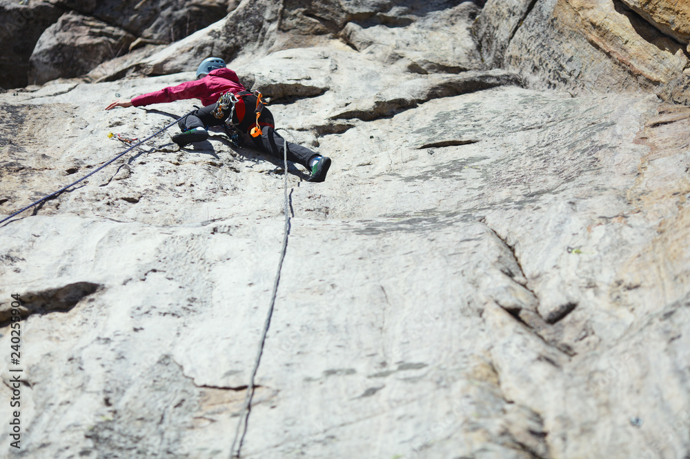 A girl climber climbs up a rock wall. Sports climbing. A girl climber climbs up a rock wall. Sports climbing.