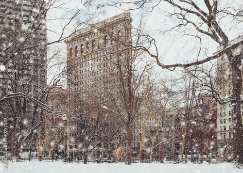 View of historic Flatiron building from Madison Square Park in New York City midtown Manhattan with snowflakes falling during winter snow storm
