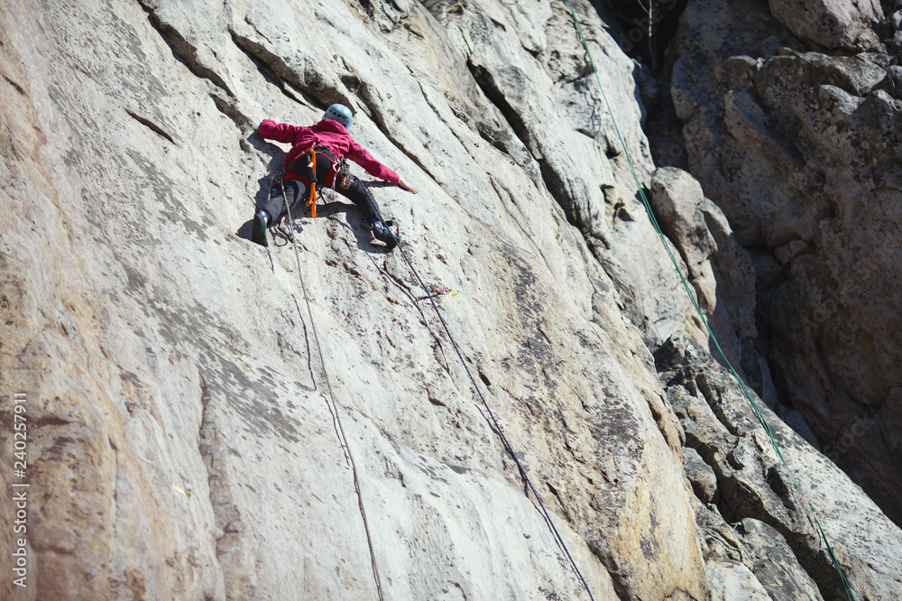 A girl climber climbs up a rock wall. Sports climbing.