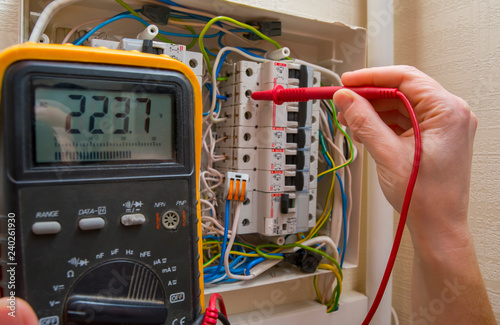 The wizard measures the voltage in the home network using a voltmeter.