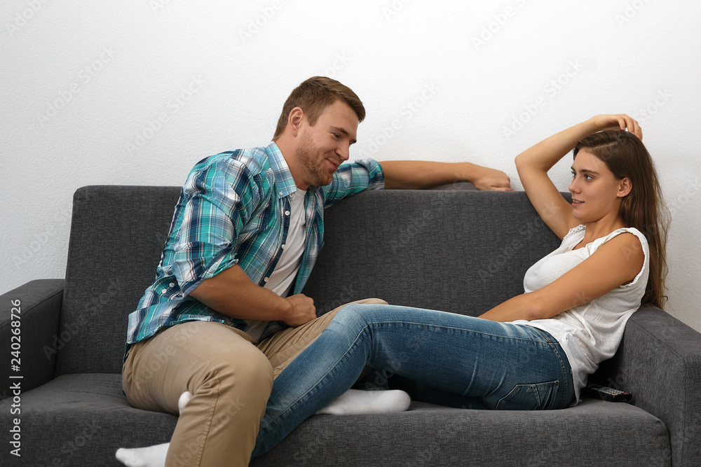 People, love, romance and dating concept. Portrait of happy young couple relaxing indoors after work. Pretty girl and bearded guy relaxing together on comfortable sofa in minimalistic living room People, love, romance and dating concept. Portrait of happy young couple relaxing indoors after work. Pretty girl and bearded guy relaxing together on comfortable sofa in minimalistic living room