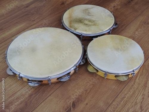 Close-up of three pandeiros  (tambourines), a Brazilian musical percussion instrument, on a wooden surface. It is widely used to accompany samba and choro, two popular Brazilian rhythms. photo