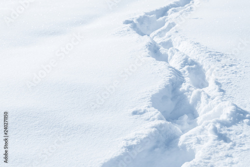 Fresh snow background texture. Winter background with snowflakes and snow mounds. Snow lumps. Footprints and traces.