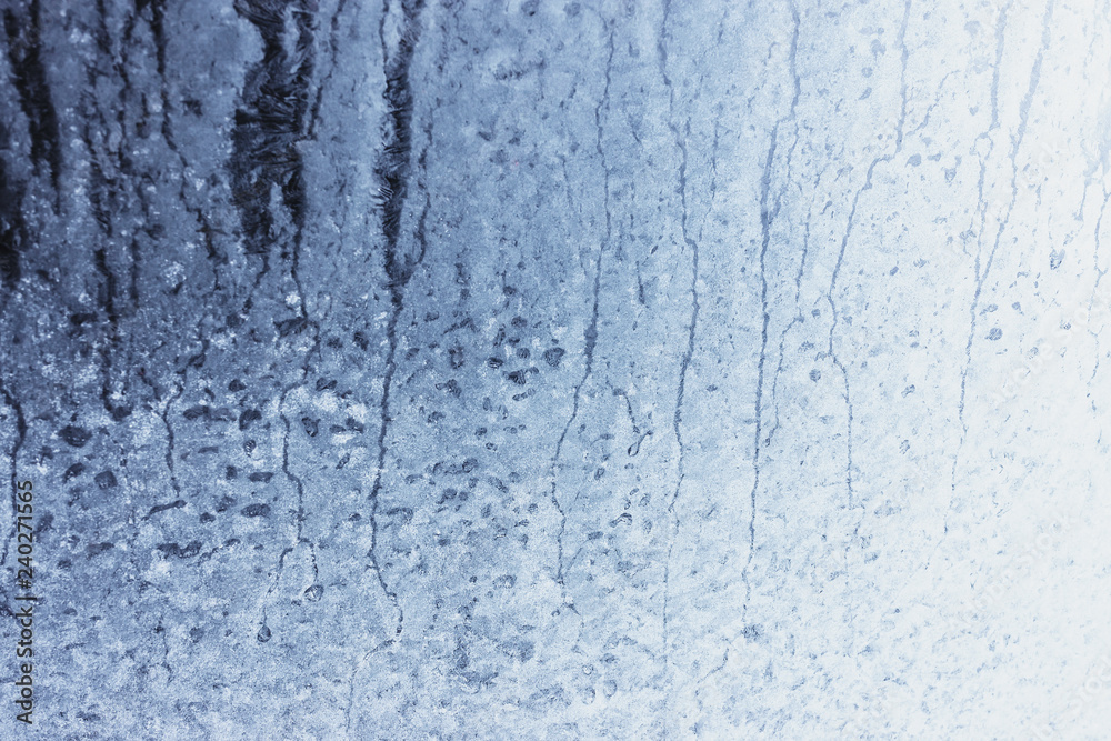 Frozen winter window pane coated shiny icy patterns. Frost background, closeup. Extreme north low temperature. Natural ice glass