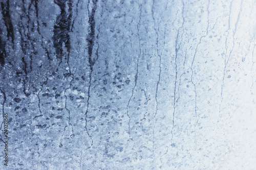 Frozen winter window pane coated shiny icy patterns. Frost background, closeup. Extreme north low temperature. Natural ice glass