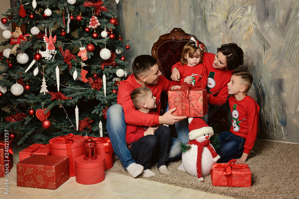 A fun young family sitting by a Christmas tree with gifts A fun young family sitting by a Christmas tree with gifts