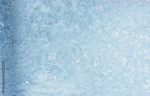 Frozen winter window pane coated shiny icy patterns. Frost background, closeup. Extreme north low temperature. Natural ice glass