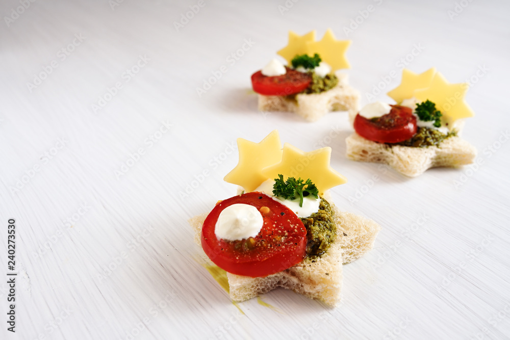 creative christmas canapes in star shape with tomato, pesto and cheese,  light background with copy space Stock Photo | Adobe Stock