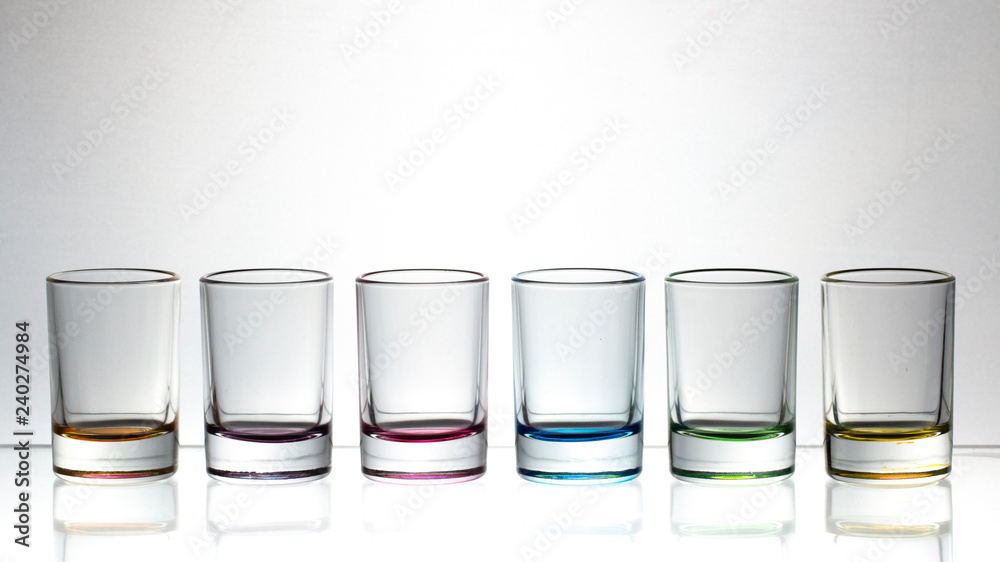 Six small multi-colored glasses on a bright background
