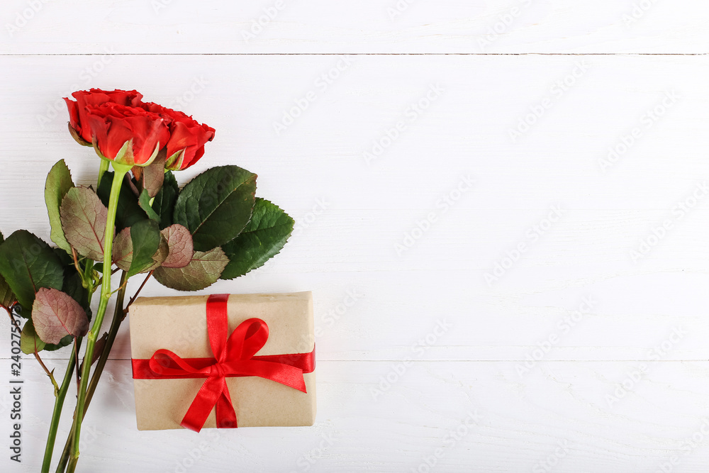 A bouquet of red roses, a gift on a white wooden table. Concept of Women's Day or St. Valentine. Copy space.