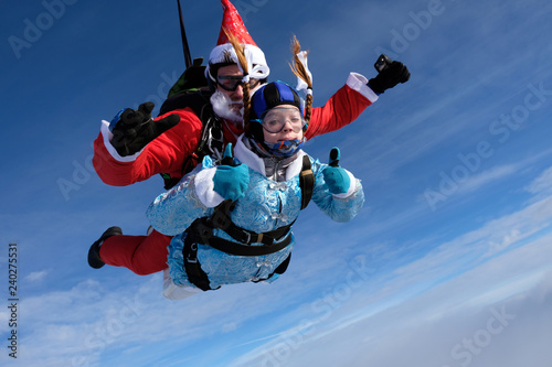 Christmas skydiving. Santa Claus and little girl are in the sky.