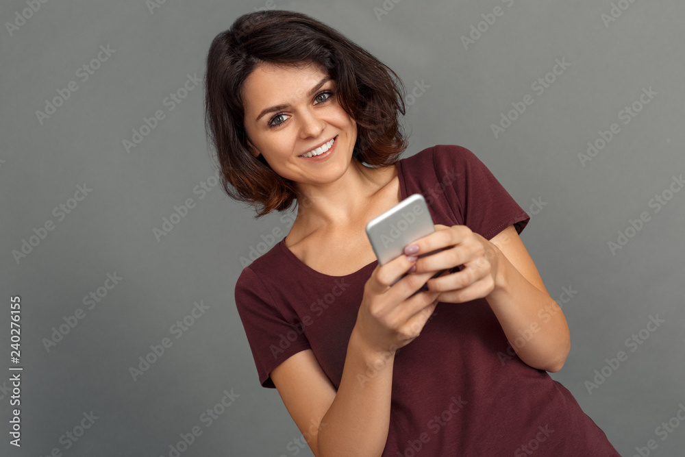 Freestyle. Young woman isolated on grey hcatting on smartphone smiling cheerful close-up Freestyle. Young woman isolated on grey hcatting on smartphone smiling cheerful close-up