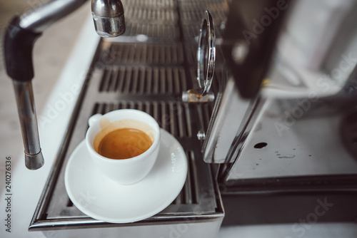 close-up view of glass cup with cappuccino and coffee machine