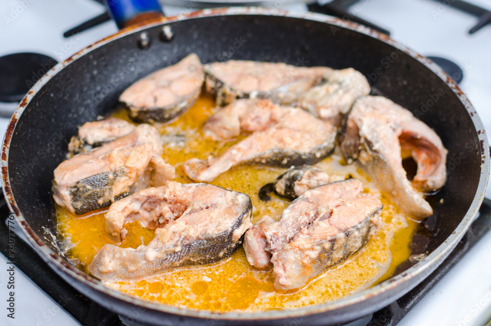 Stewed red salmon fish in tomato sauce in a frying pan Stewed red salmon fish in tomato sauce in a frying pan