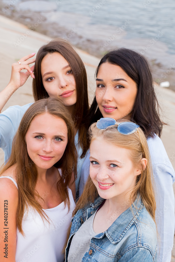 Close up portrait of four young beautiful girlfriends in summer on the beach