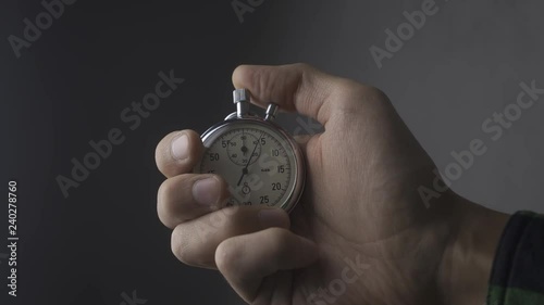 Close-up of one person starting up a stopwatch at grey background. 4K, 10 BIT, 4:2:2.
