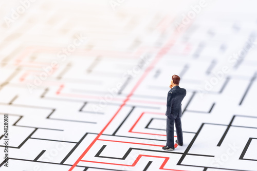Miniature people, businessman in the labyrinth or maze figuring out the way out. Business concept, finding solution, strategic, and business opportunity.