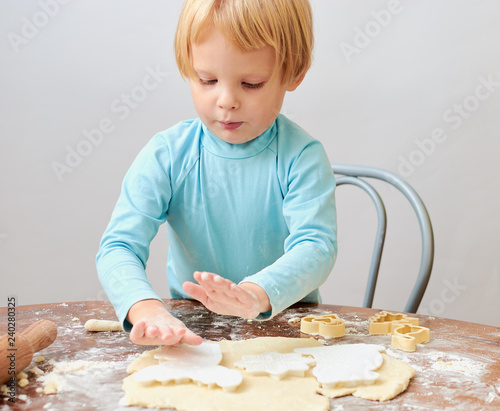child makes cookies from dough on the table