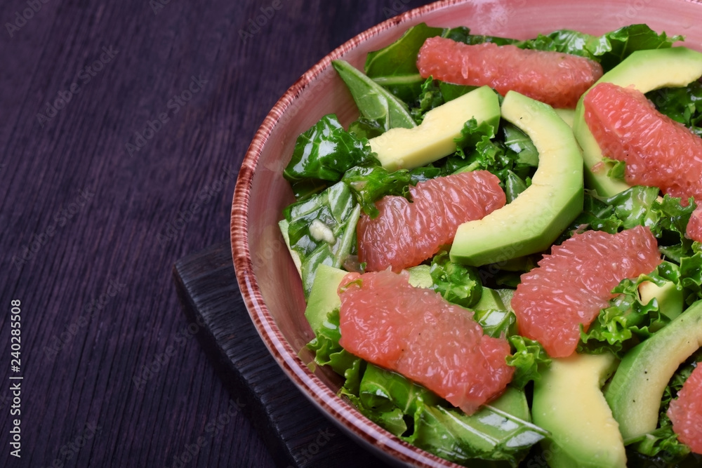 Salad with kale, avocado and grapefruit against the dark background