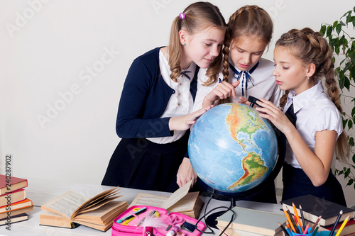 three girls in the classroom studying geography globe of planet Earth