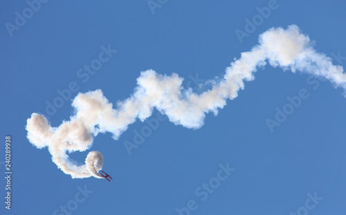 Vintage biplane makes smoke trails in the sky over San Diego