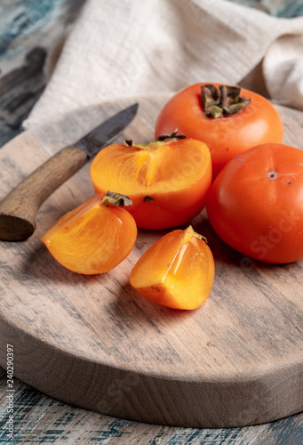 Fresh persimmon fruits on board and knife
