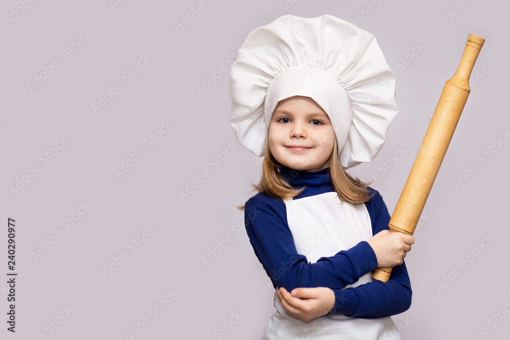 Children cook. Happy little girl in chef uniform holds rolling pin isolated on white background Children cook. Happy little girl in chef uniform holds rolling pin isolated on white background