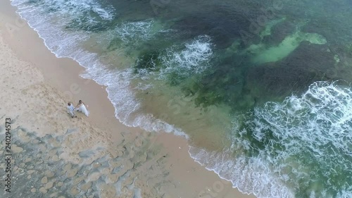 Aerial view from drone of wedding couple walkin at beach.
