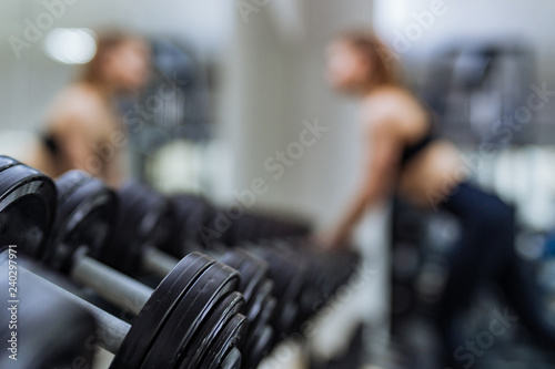 Row of dumbbells near the mirror on the background of sport gym with a female. Close-up. Sports concept and a healthy lifestyle.