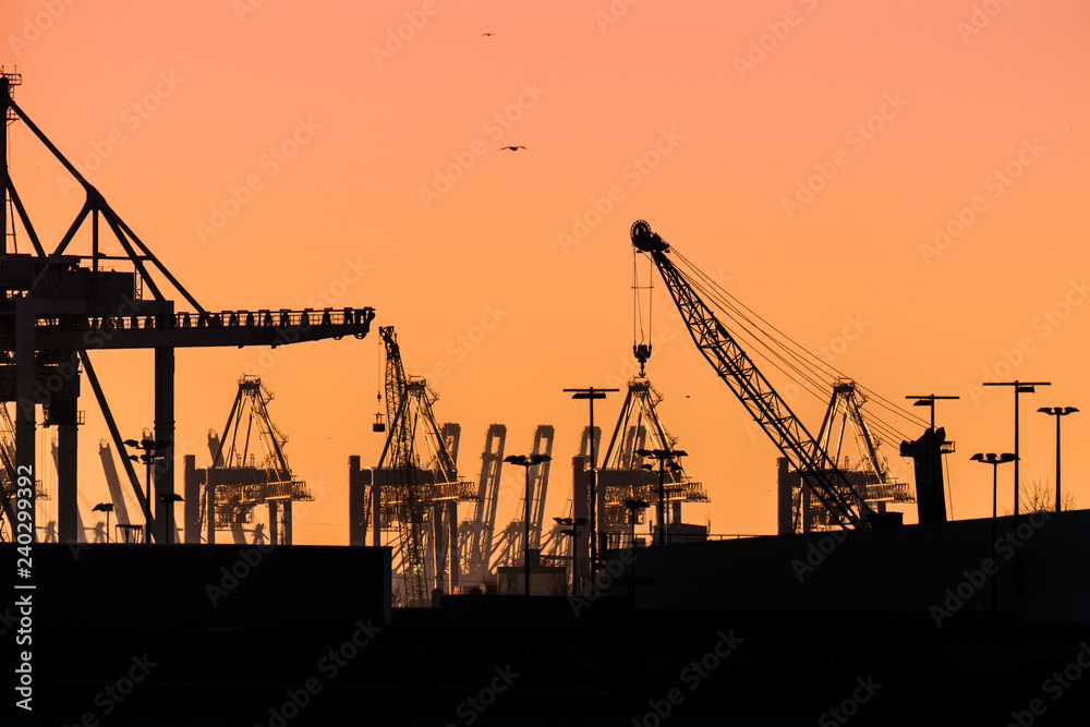 Cranes silhouetted against the evening sky in Hamburg Harbor, Germany, at dusk. The Port of Hamburg (Hamburger Hafen) is a sea port on the river Elbe. It is Germany's largest port.