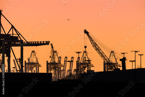 Cranes silhouetted against the evening sky in Hamburg Harbor, Germany, at dusk. The Port of Hamburg (Hamburger Hafen) is a sea port on the river Elbe. It is Germany's largest port.