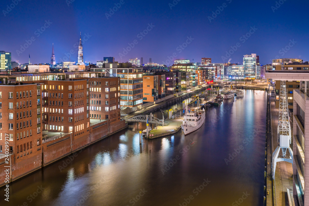 The Harbor District (HafenCity) in Hamburg, Germany, at night. Panoramic aerial view of the Sandtorkai and the Kaiserkai across the traditional port Sandtorhafen.