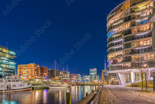 The Harbor District (HafenCity) in Hamburg, Germany, at night. A view of the Sandtorkai and the Kaiserkai across the traditional port Sandtorhafen. photo