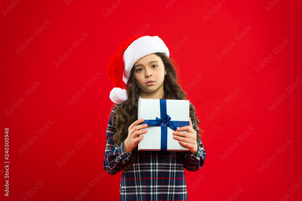 New year party. Santa claus kid. Christmas shopping. Present for Xmas. Childhood. Little girl child in santa red hat. Happy winter holidays. Small serious girl. Merry Christmas and Happy Holidays New year party. Santa claus kid. Christmas shopping. Present for Xmas. Childhood. Little girl child in santa red hat. Happy winter holidays. Small serious girl. Merry Christmas and Happy Holidays