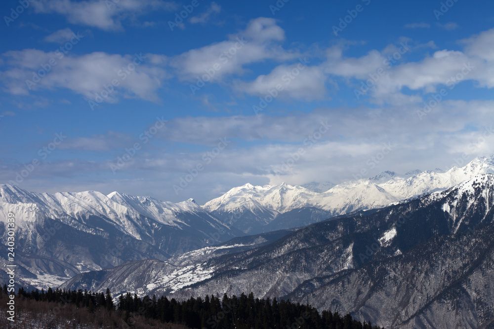 Snowy mountains and blue sky with clouds at winter sun day