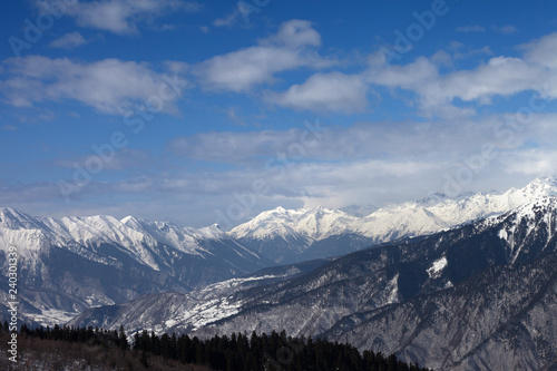 Snowy mountains and blue sky with clouds at winter sun day © BSANI