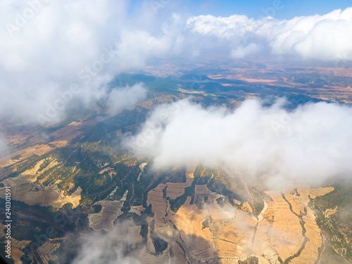 View from the window of the aircraft: mountains, fields, roads, villages, clouds