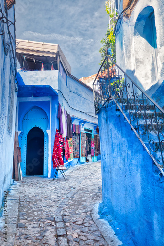 Typical street of the Medina of Chefchaouen with small souvenir shops that display their products on the street. In Morocco, North Africa © juanorihuela