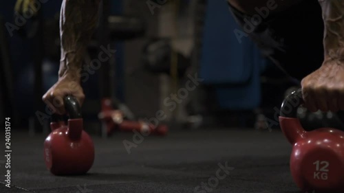 Adult male athlete with tattoos on his arms exercising in the gym.